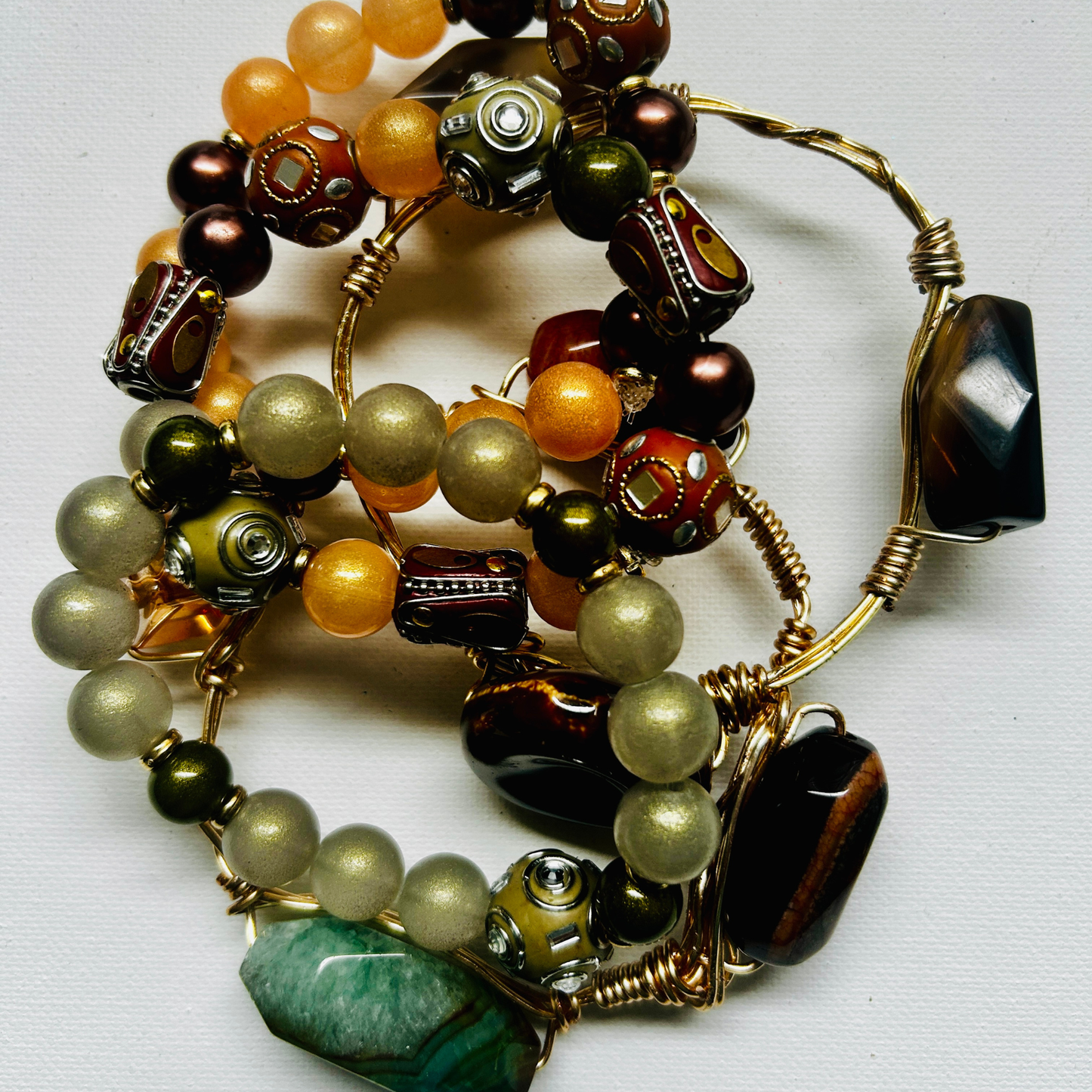 “Stack of handcrafted gemstone bracelets with gold wire wrap, earthy beads, and polished stones – boho spiritual jewelry”