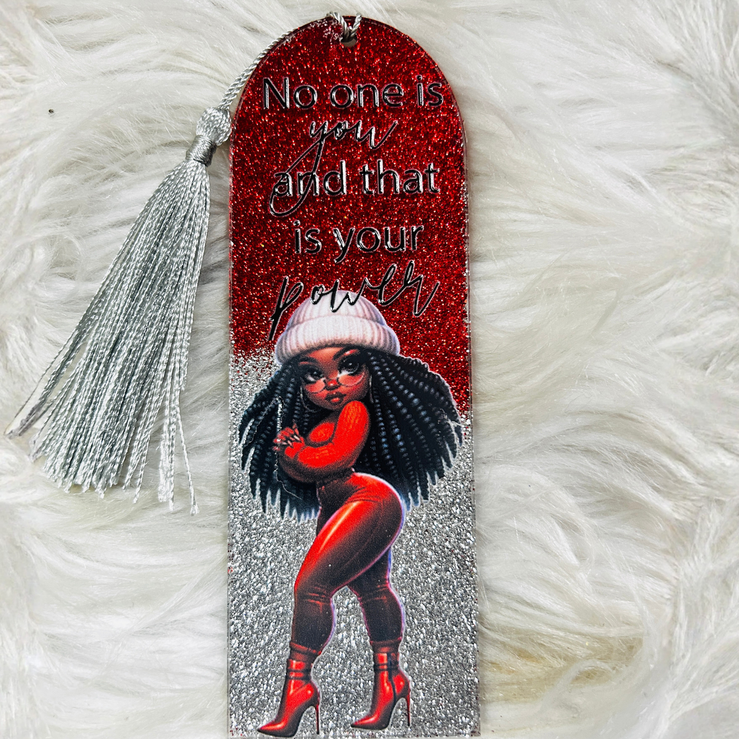 A red and silver glitter resin bookmark with a silver tassel featuring a confident Black woman illustration and the quote: "No one is you and that is your power."