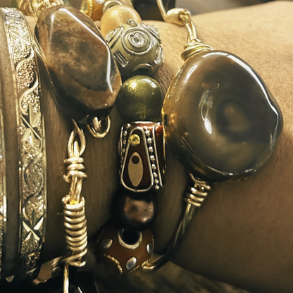 Close-up of a bracelet with various beads and metallic elements on a wrist.
